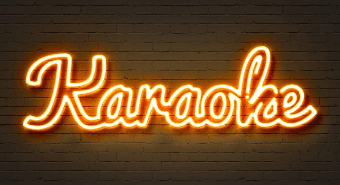 Neon sign spelling 'karaoke' on a brick wall.