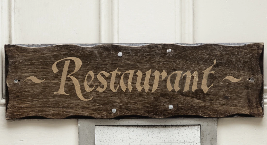 Rustic wooden restaurant sign mounted on a wall.