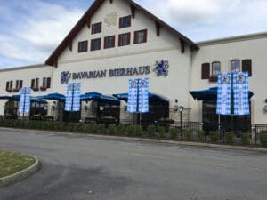 Exterior of bavarian bierhaus restaurant with blue and white striped awnings and large signage. no people visible, daytime setting.