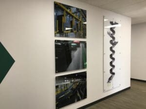 Modern office wall decorated with framed photographs displaying different industrial scenes, including machinery and assembly lines.