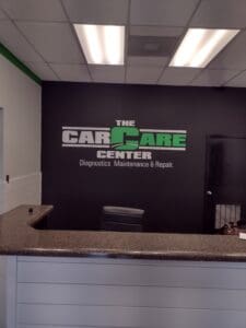 Reception counter at the car care center with a dark gray wall featuring the company's logo and services offered.