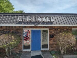 Front view of a chiropractic office named "chiro4all" with a blue door, a heart-covered window, and business hours posted on the door.
