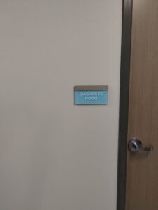 A closed door with a sign reading "diagnostic room" next to a door handle, indicating a medical examination area.