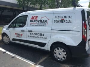 White commercial van parked outdoors, branded with ace handyman services logo, advertising residential and commercial services, and displaying a phone number.