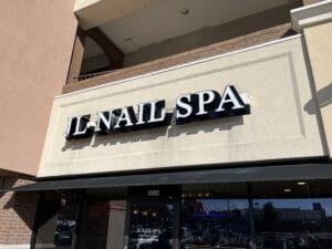 Exterior view of "jl nail spa" storefront with bold signage above the entrance under a sunny sky.
