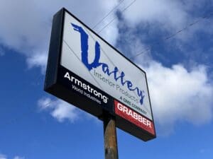 Large roadside billboard for "thayer's interior products," a gms company, featuring logos of armstrong and graber against a blue sky with clouds.