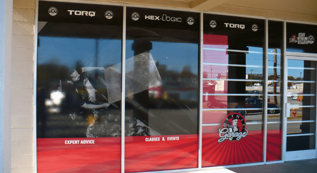 Storefront with large promotional posters displaying "Torq" and "Hex-Logic" logos, expert advice, classes & events, and an image of an individual polishing a vehicle. Red, black, and white color scheme.