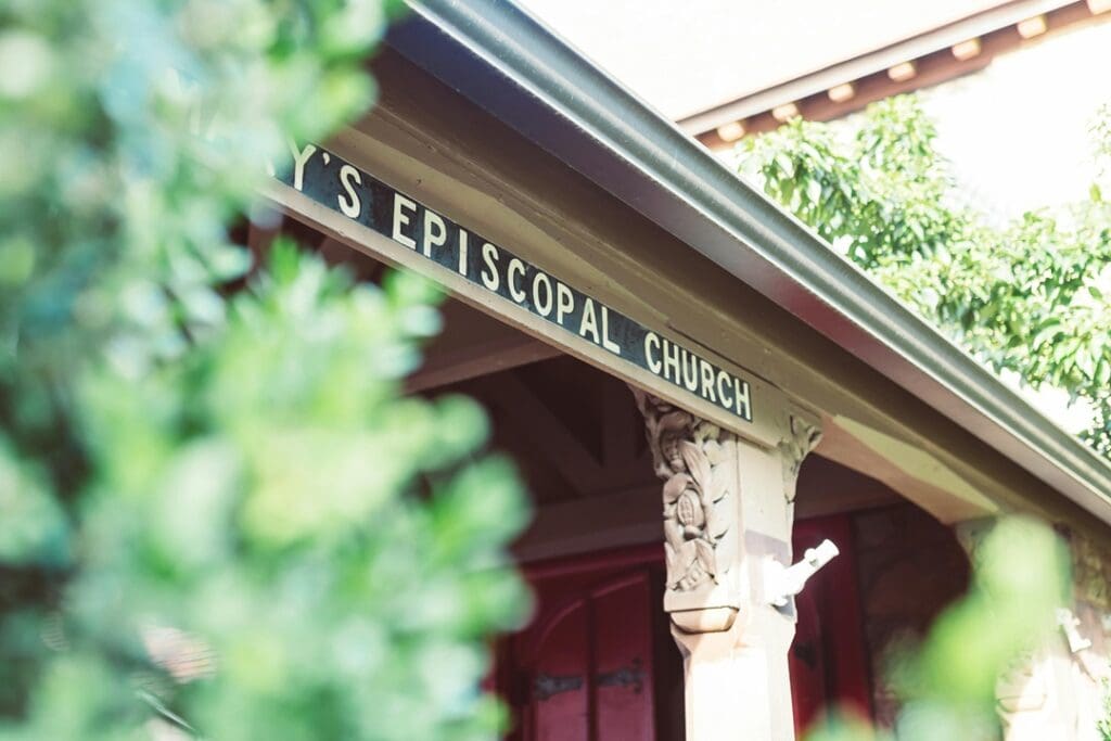 Church Sign Nashville View of a church entrance with the sign "Episcopal Church." The entrance features decorative carvings and a red door, partially obscured by greenery in the foreground.
