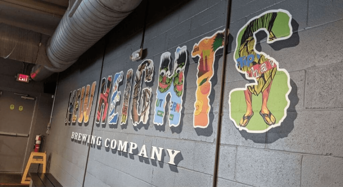 A mural on a gray wall reads "HIGHLAND HEIGHTS BREWING COMPANY" in large colorful letters with collage-style artwork inside each letter.