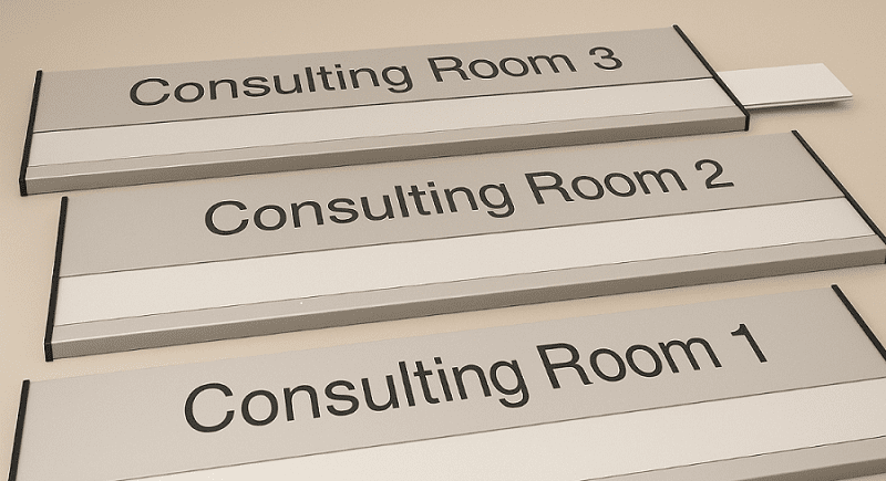 Three rectangular signs read "Consulting Room 1," "Consulting Room 2," and "Consulting Room 3," arranged on a flat surface.