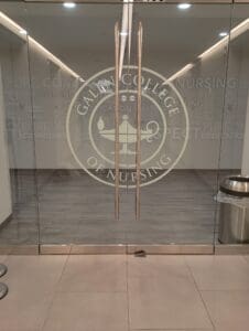 Glass doors with the Galen College of Nursing logo and words like "discipline" and "respect"; a trash can and a key are on the floor in front of the doors.
