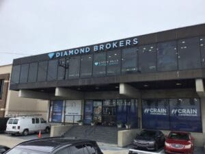 A two-story commercial building houses Diamond Brokers on the upper level and Crain Construction on the lower level, with a parking lot in front and several vehicles visible.