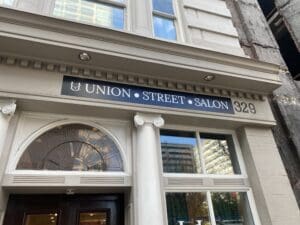 The exterior of Union Street Salon at 329, with a black and white sign above the entrance and large windows reflecting nearby buildings.