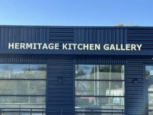 Exterior of a building with large letters reading "HERMITAGE KITCHEN GALLERY" above windows and under a clear blue sky.