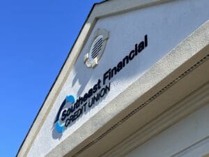 The exterior of a building displays the sign "Southeast Financial Credit Union" against a clear blue sky.