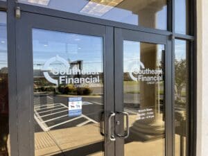 Glass entrance doors of Southeast Financial Credit Union showing the logo, business hours, and a small sign displaying pet rules.