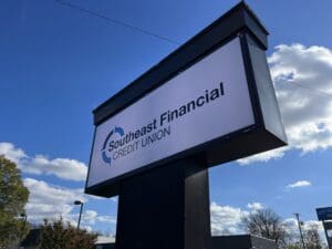 A large outdoor sign displays the logo and name "Southeast Financial Credit Union" against a blue sky with scattered clouds.