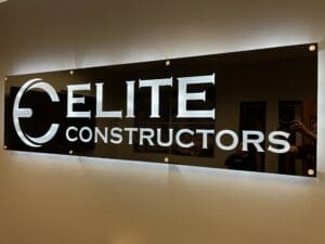 A wall-mounted sign with the illuminated text "ELITE CONSTRUCTORS" in bold letters on a glass or acrylic panel.