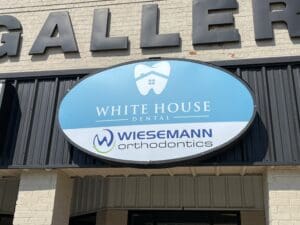 A blue and white sign reads "White House Dental" above "Wiesemann Orthodontics" with a tooth and house icon on a building exterior.