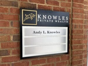A sign on a brick wall reads "KNOWLES PRIVATE WEALTH" with a bull logo above the name "Andy L. Knowles.
