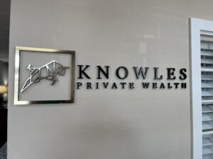 Wall sign reads "Knowles Private Wealth" with a metallic geometric bull icon framed on the left.