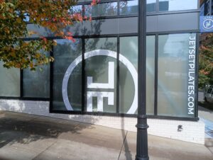 Large windows display the JetSet Pilates logo and website URL "JETSETPILATES.COM" on the exterior of a building, with a tree and sidewalk in the foreground.
