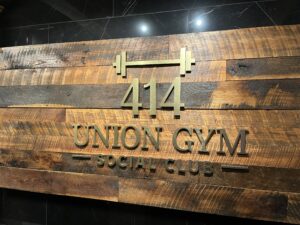 A wooden wall sign reads "414 Union Gym Social Club" with a barbell icon above the numbers.